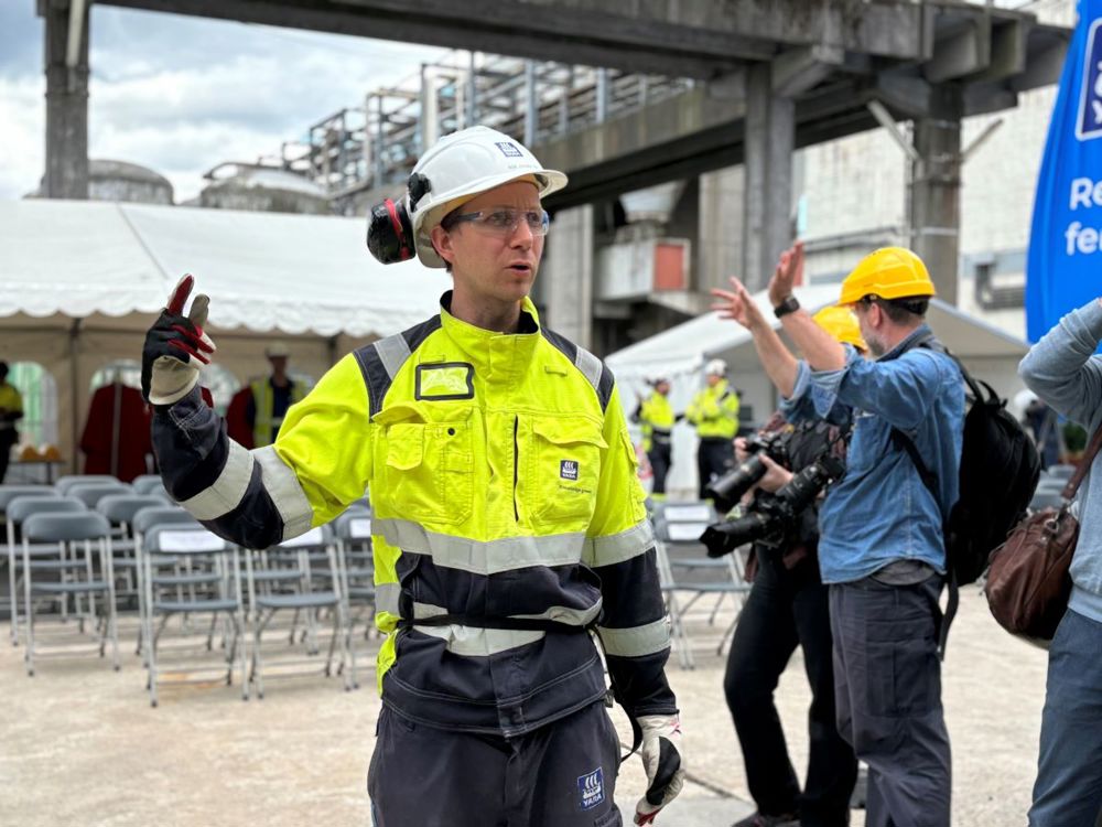 young man, PPE, guiding the press around in the plant.