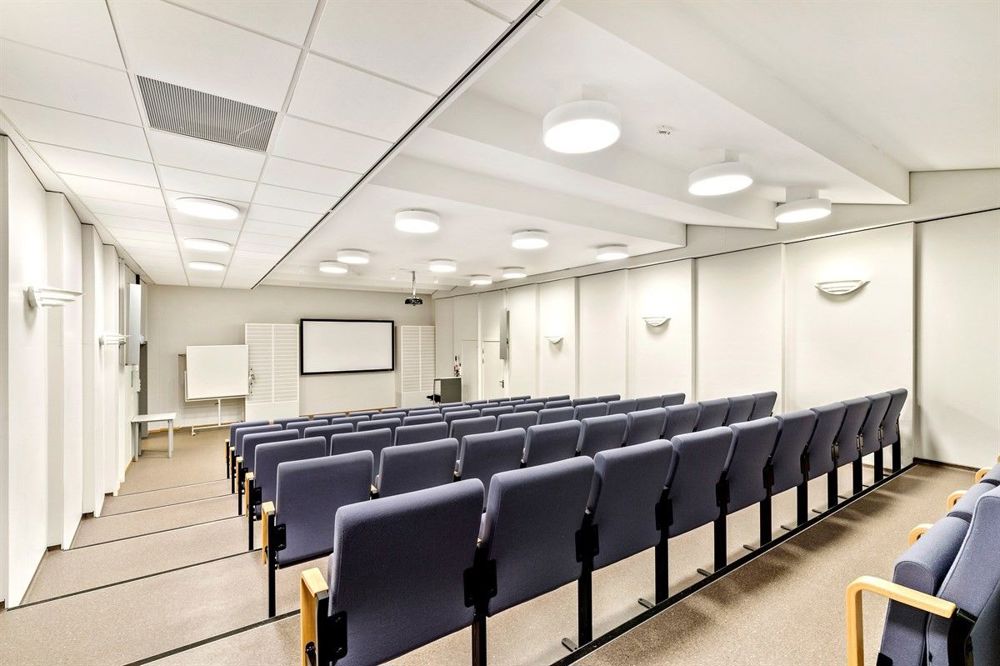 auditorium, white walls, rows of blue chairs
