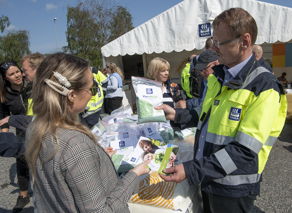 mann i Yara-jakke snakker ved kvinnelig gjest og viser gjødselprodukt på stand