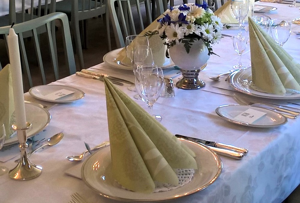 a set table, white table cloth, china, silvery and napkins, flowers and candle