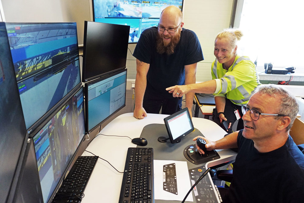 three people in an office eganged around monitors