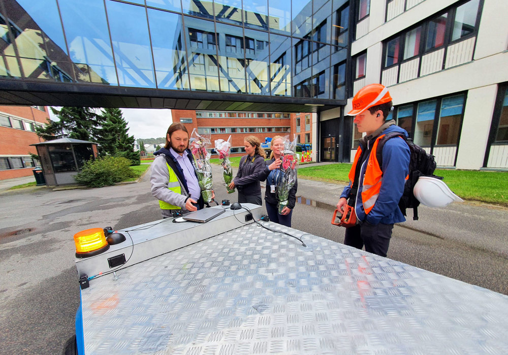 four people standing at the far end of the robot