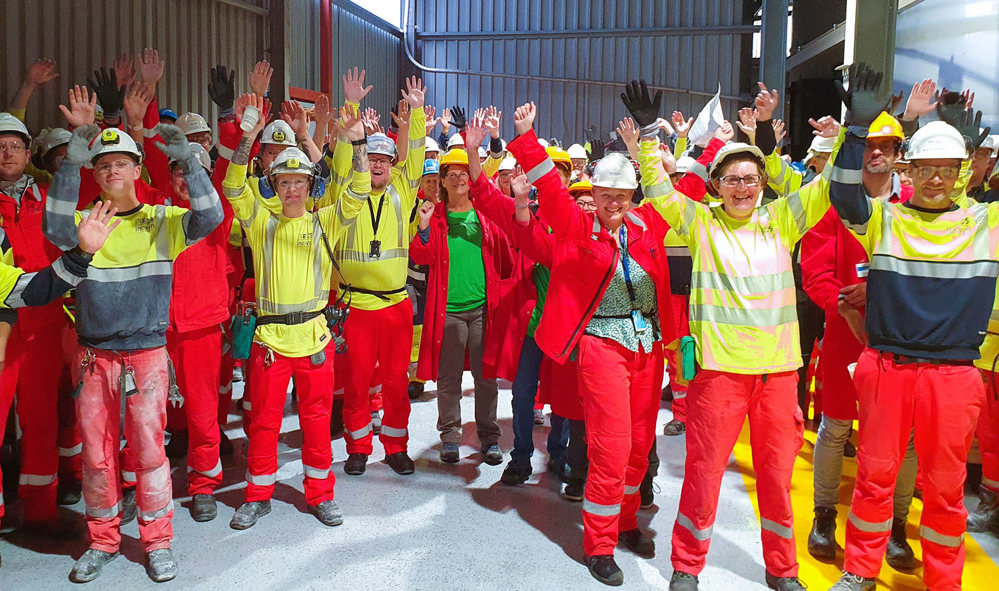 great crowd raising their arms in celebration, production hall