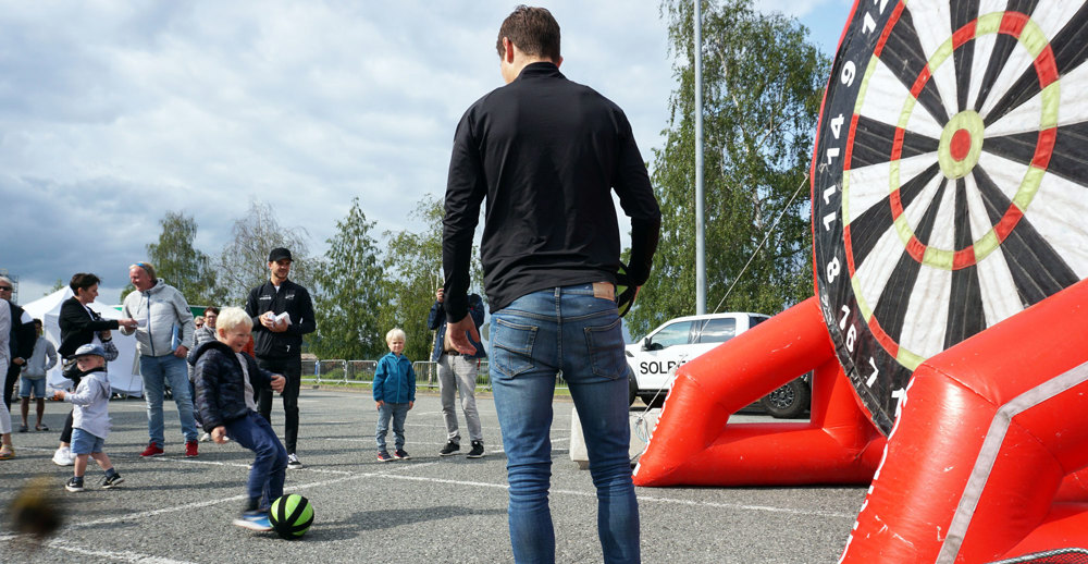 liten gutt skyter på kjempestor dart-skive med poengskala