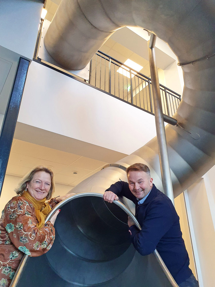 man and woman sitting next to tube slide, office environment