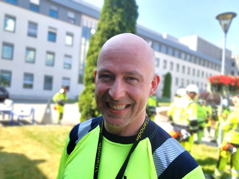 portrait of man, no hair, standing in a park area outside office building