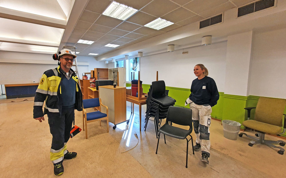 two people getting offices ready, painting, tidying