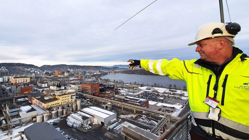 mann står på en høyde og peker utover industriparken.