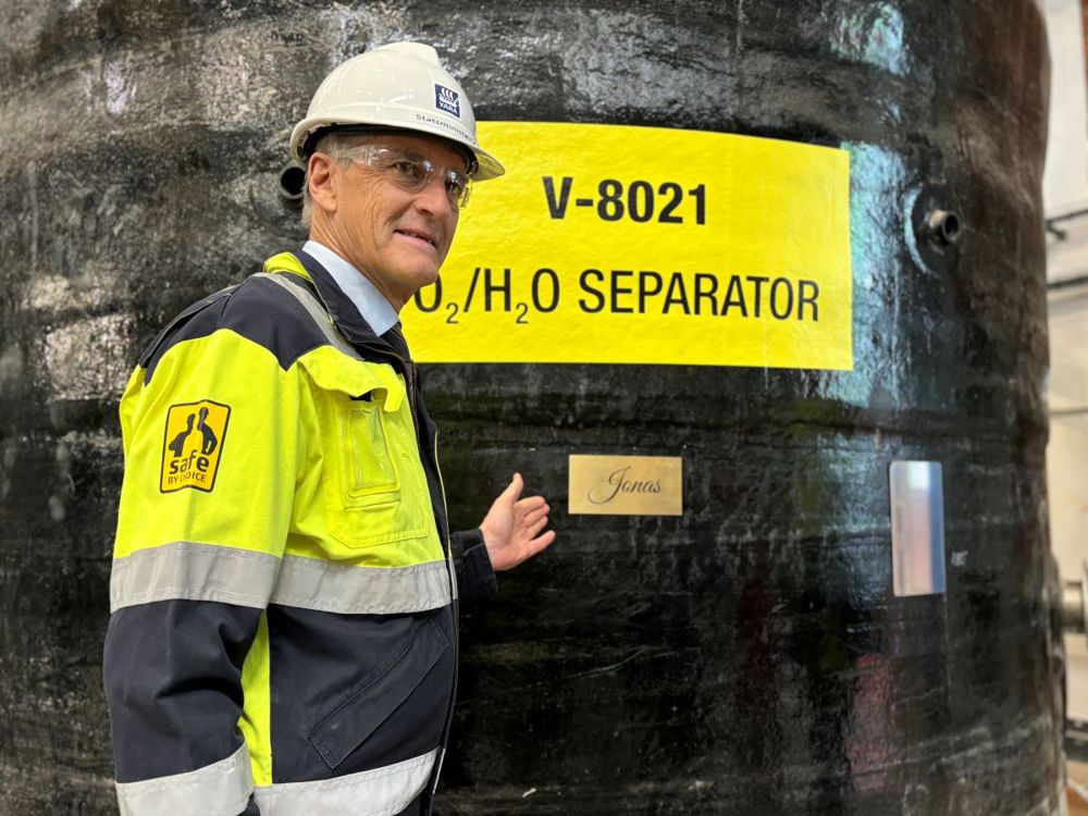 prime minister standing next to tank with his name on a plague.