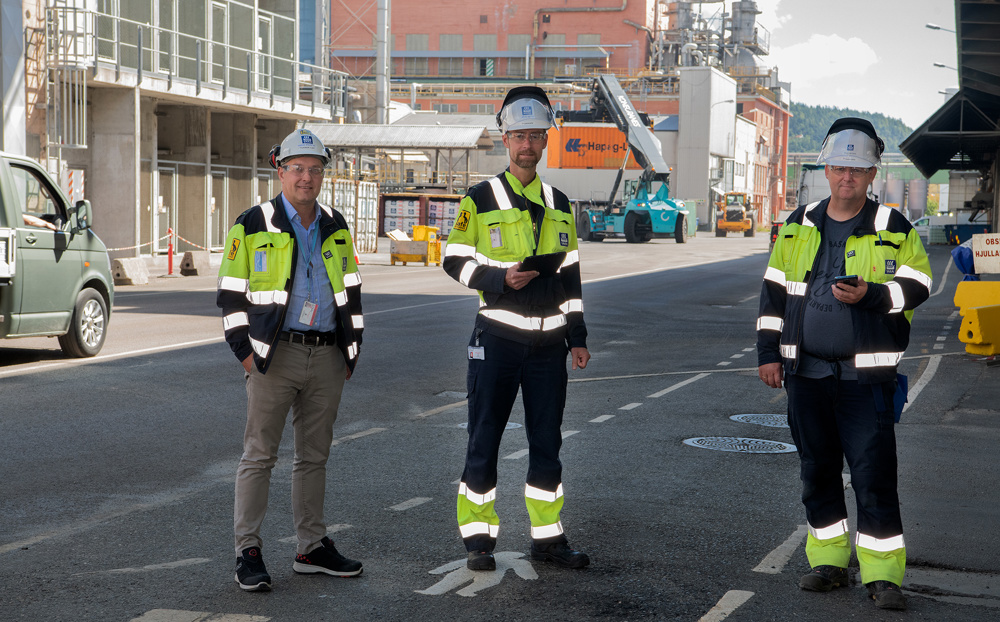 three men standing, posing, in a street, industrial park