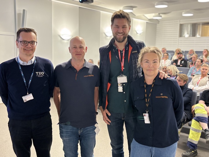 fire personer foran fullsatt auditorium i bakgrunnen