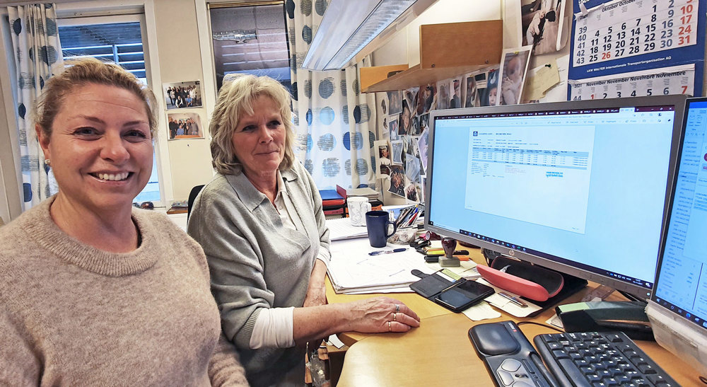 two women sitting at a desk in office