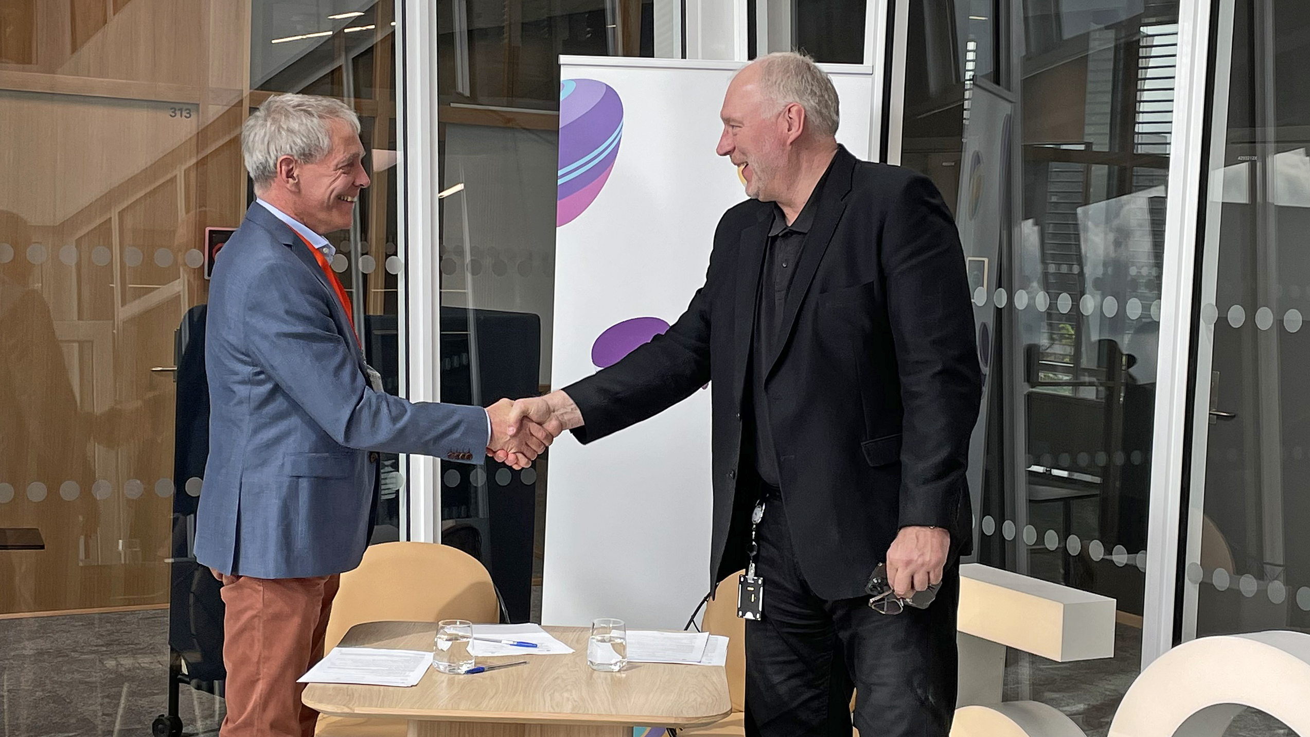 two men standing and shaking hands over deal