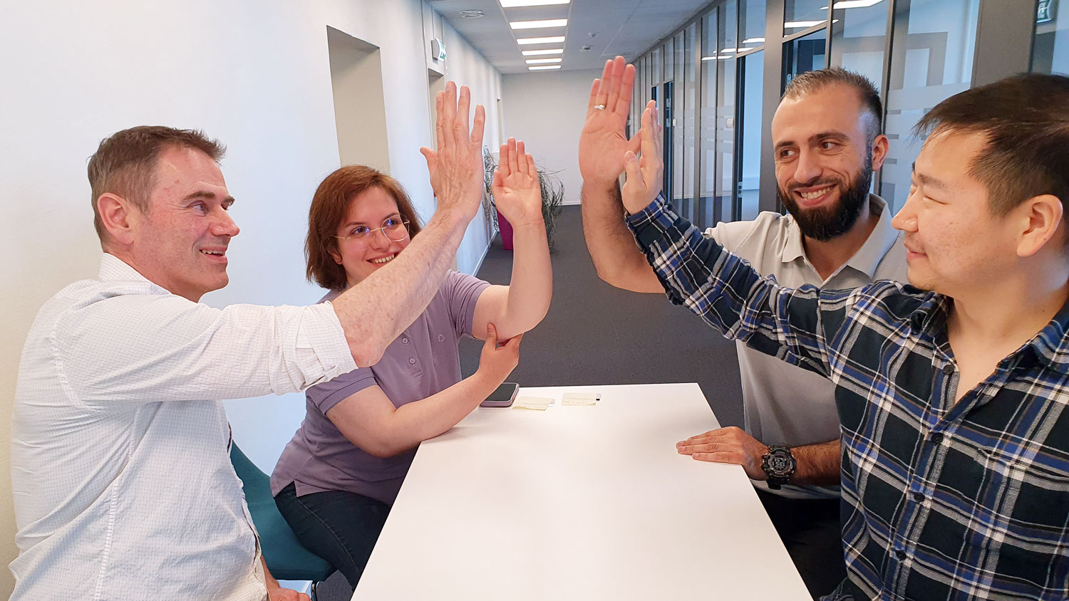 four people at a table, high five, office environment