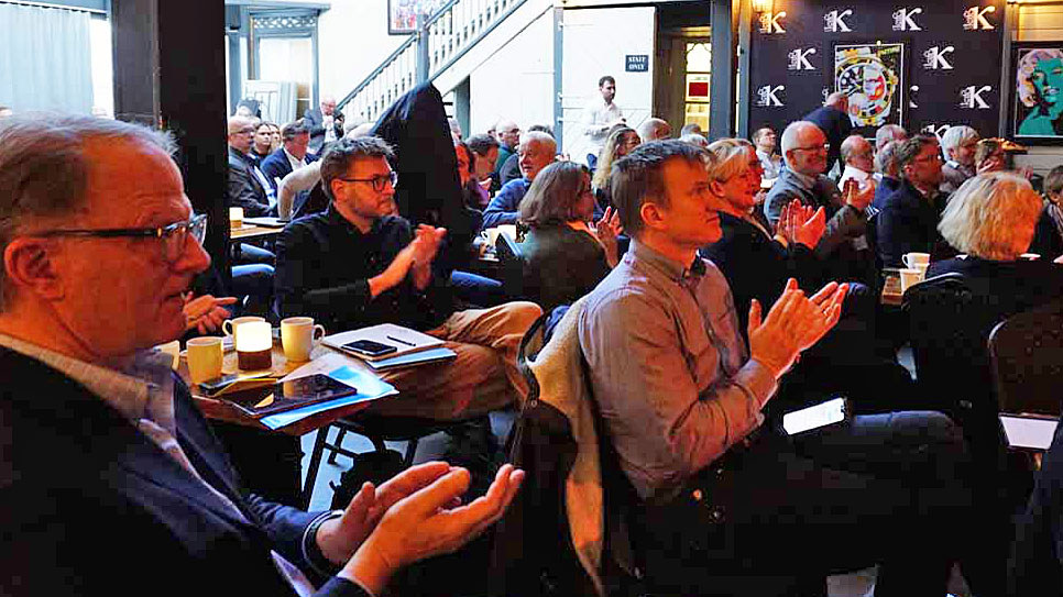 publikum i salen med småbord klapper