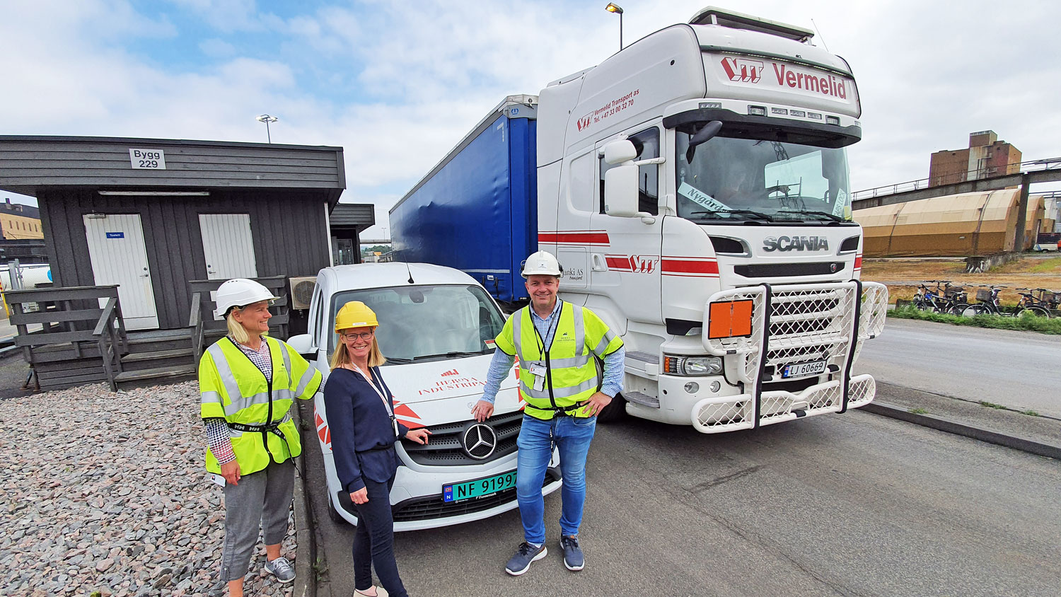 three persons standing by a small vehicle next to a truck