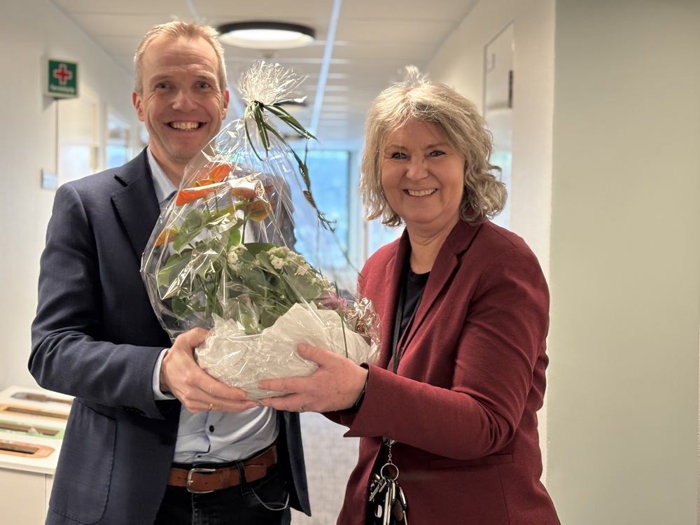 two people, one presenting flowers to the other, office space