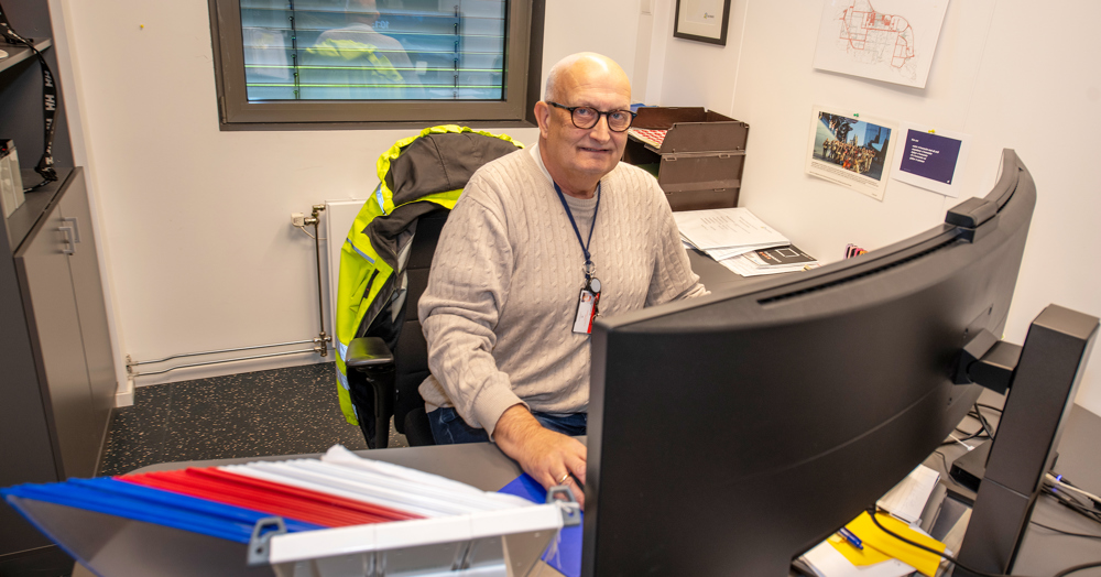 man sitter ved arbeidsplass, poserer, stor buet skjern.