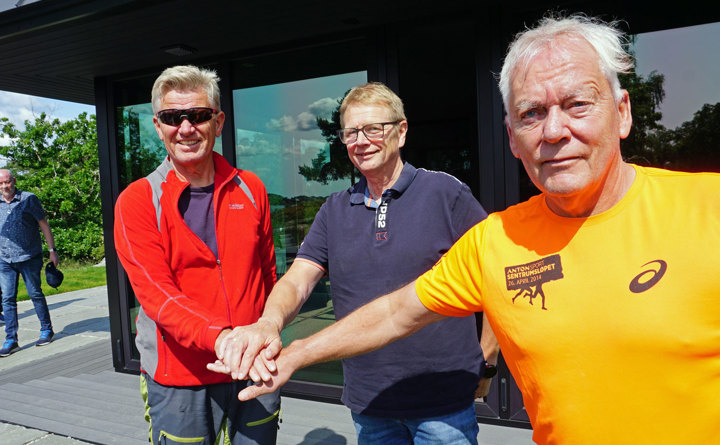 tre menn, poserer, strekker frem hver sin hånd og holder hendene over hverandre