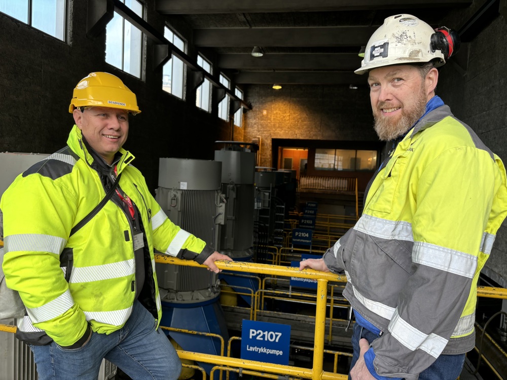 two men standing in a operations hall, posing, PPE