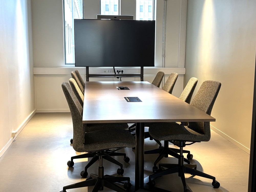 møterom med stoler og bord og monitor foran vinduer