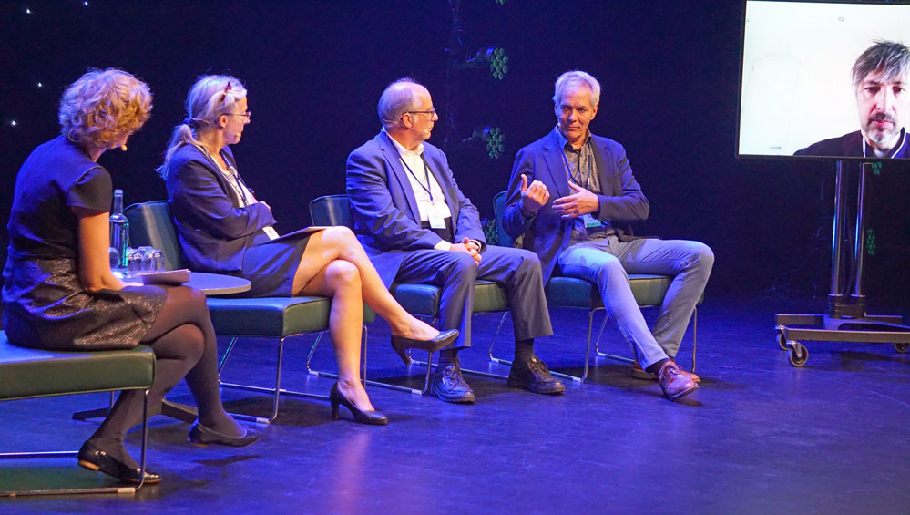 paneldebattanter snakker sammen på scenen