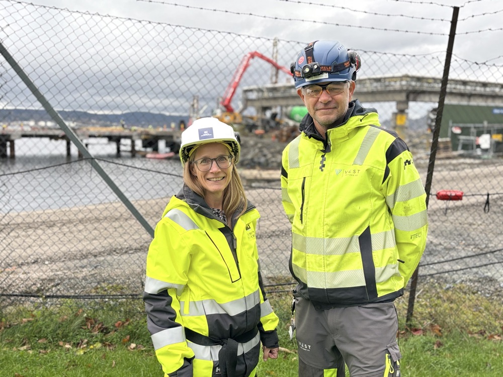 two persons, posing, quay in background, wire fence