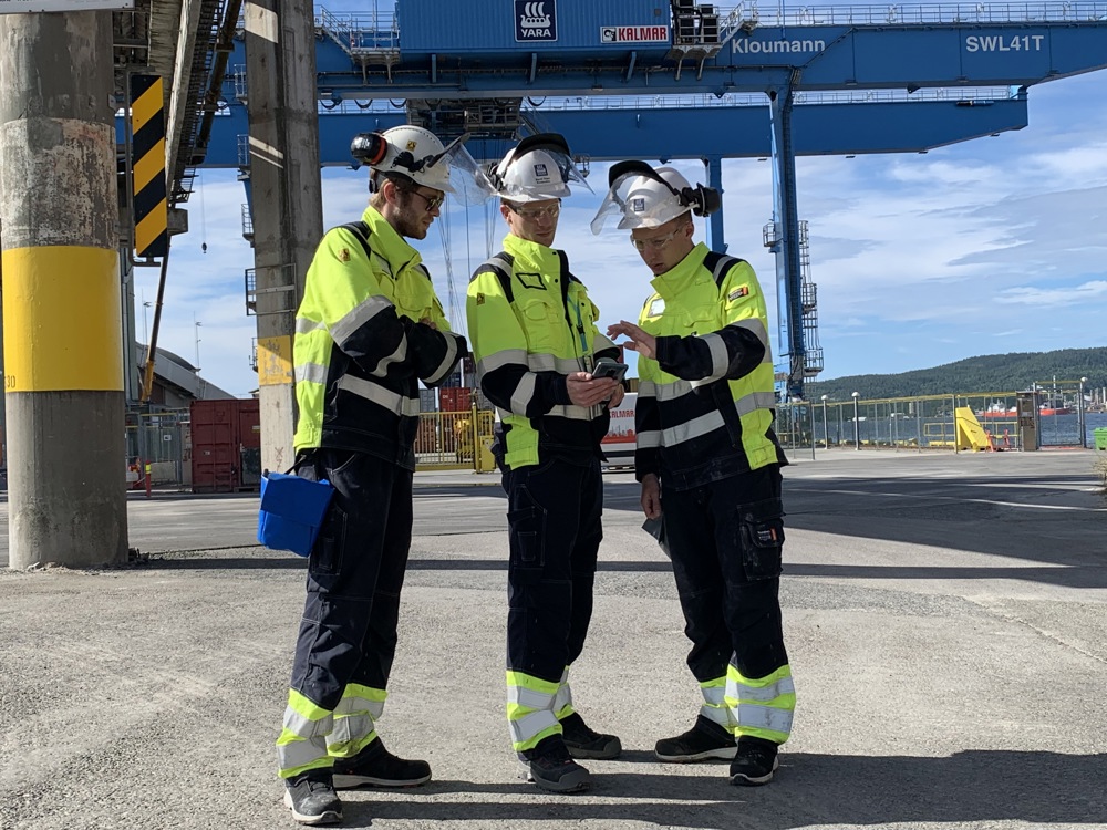 three students on a job testing 5G coverage outside in the industrial park.